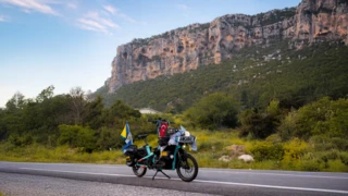 Mit Souvenirs vollbepacktes mintblaues Ca Go CS auf eineer Straße mit einem großen Sandsteinmassiv im fernen Hintergrund