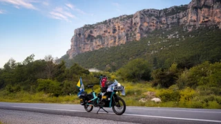 Mit Souvenirs vollbepacktes mintblaues Ca Go CS auf eineer Straße mit einem großen Sandsteinmassiv im fernen Hintergrund