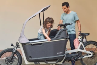 Mädchen steigt in die Transportbox des FS Life. Vater steht daneben.