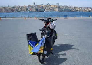 Buraks Ca Go CS steht am Ufer. Im Hintergrund ist eine Stadt zu sehen