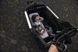 Transportsbox des FS200 Life Family mit montierter Babyschale. Darin liegt ein Baby.