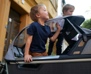 Ein fröhlich blickender Junge drückt sich durch das Fenster einer EPP-Box mit All-Weather-Top eines stehenden FS Life.