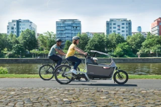 Mann und Frau fahren mit Fahrrädern über einen Weg. Die Frau fährt ein FS Life, in der Box sitzt ein Kind.