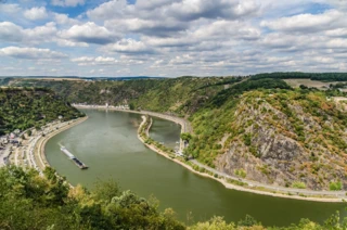 Blick auf den Rhein und die Loreley von einem Berg aus. Im Wasser fährt ein Schiff.