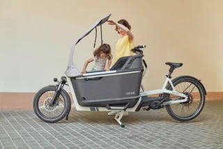 Ein Mädchen klettert in die Box des FS200 Life. Währenddessen hält die Mutter das All-Weather-Top fest.