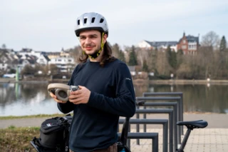 Mann trägt einen Fahrradhelm und hat Kopfhörer in der Hand