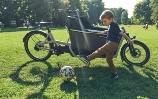 Ein Kind spielt in einem Park vor einem FS Life mit einem Fussball.