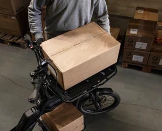 Ein Mann belädt das Front Rack eines CS mit einem großen Paket.