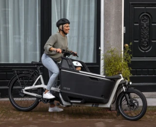 Eine Mutter beginnt bei einem FS Life zu pedalieren, während ein Kind in der EPP-Box sitzt.