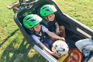 Zwei Jungs sitzen in der Transportbox am FS Life. Einer der beiden hält einen Fußball in der Hand.