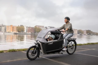 Mutter und Kind fahren im FS200 Life Plus an einem Fluss entlang.