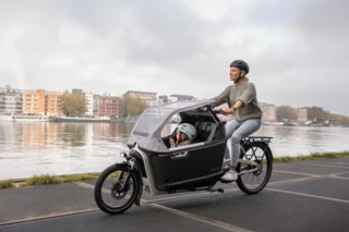Mutter und Kind fahren im FS200 Life Plus an einem Fluss entlang.