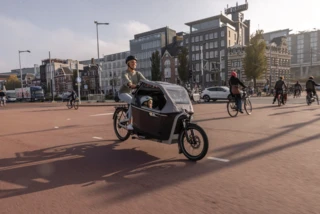 Vrouw rijdt met FS Life door Amsterdam. In de box zit een kind.
