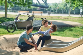 Eine Familie ist auf einem Spielplatz. Im Hintergrund steht ein FS200 Life Family Plus