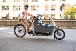 Frau fährt mit FS Life durch die Stadt. In der Transportbox sitzt ein Kind.
