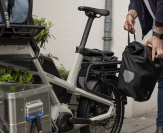 Ein Mann hängt eine Tasche an die MIK-Schnittstelle des CS Rear-Racks.