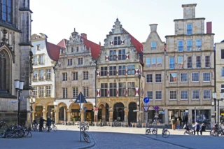 Blick auf den Prinzipalmarkt in Münster. Zu sehen sind alte Gebäude an einer Straße. An den Straßenrändern sind einige Fahrräder abgestellt.