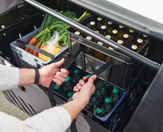 Eine Person Lädt Lebensmittel- und Getränkekisten in ein FS Vario.